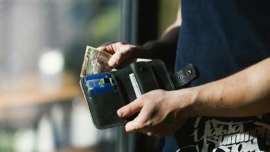 photograph of person holding black leather wallet with money