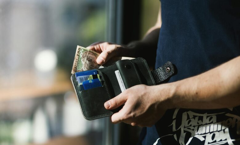 photograph of person holding black leather wallet with money